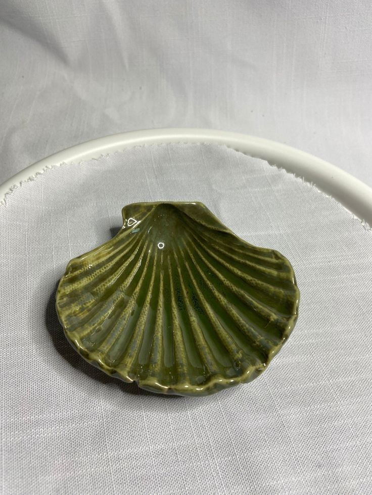 a green shell shaped dish sitting on top of a white plate