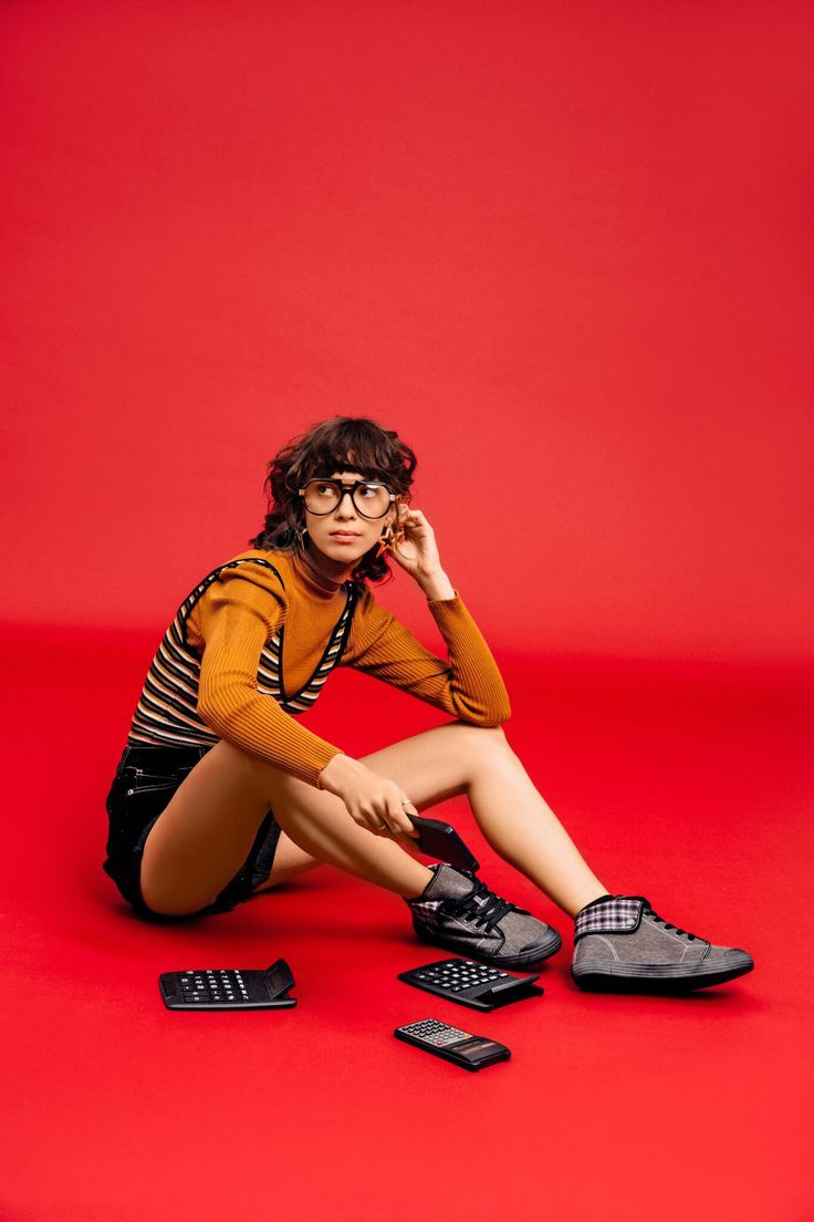 a woman sitting on the ground with her legs crossed and shoes in front of her