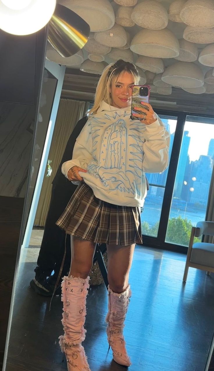 a woman taking a selfie in front of a mirror wearing pink boots and a white sweater