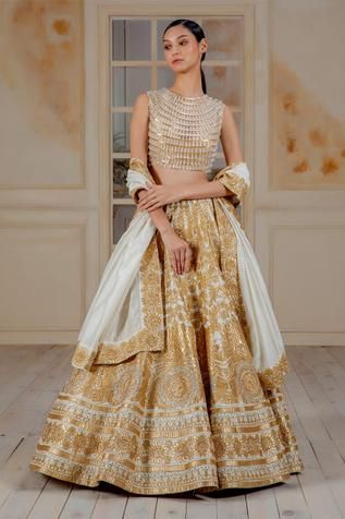 Ivory taffeta 20 kali lehenga with gold applique and crystal highlights Comes with blouse enhanced with chandelier crystals- striped work and chanderi dupatta.
Components:3
Embroidered
Neckline:Round
Sleeve Length:Sleeveless
Fabric:Blouse: Net; Lehenga: Taffeta; Dupatta: Chanderi
Color:Gold, White
Striped pattern
Crystal tassels
Closure: Blouse: Back zip - Aza Fashions Kali Lehenga, Lehenga Designs Latest, Mirror Work Lehenga, Gold Shades, Bridal Sari, Chanderi Dupatta, Gold Applique, Chandelier Crystals, Partywear Dresses