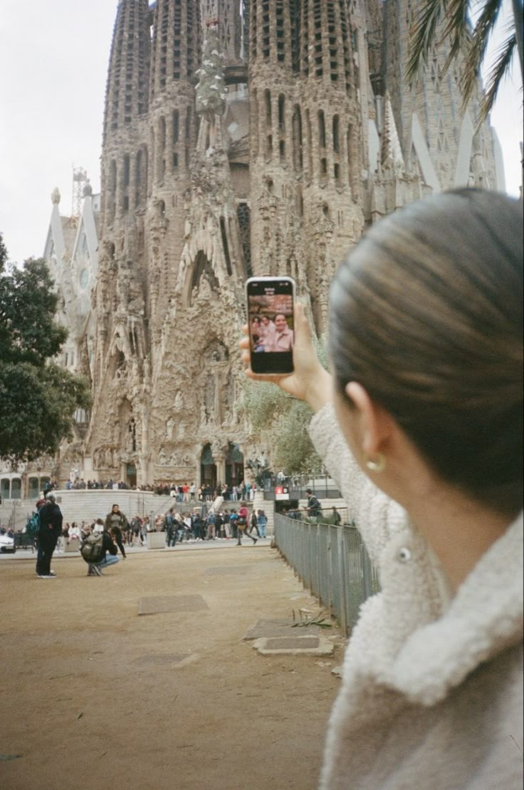 a woman is taking a photo with her cell phone in front of the sagradski cathedral