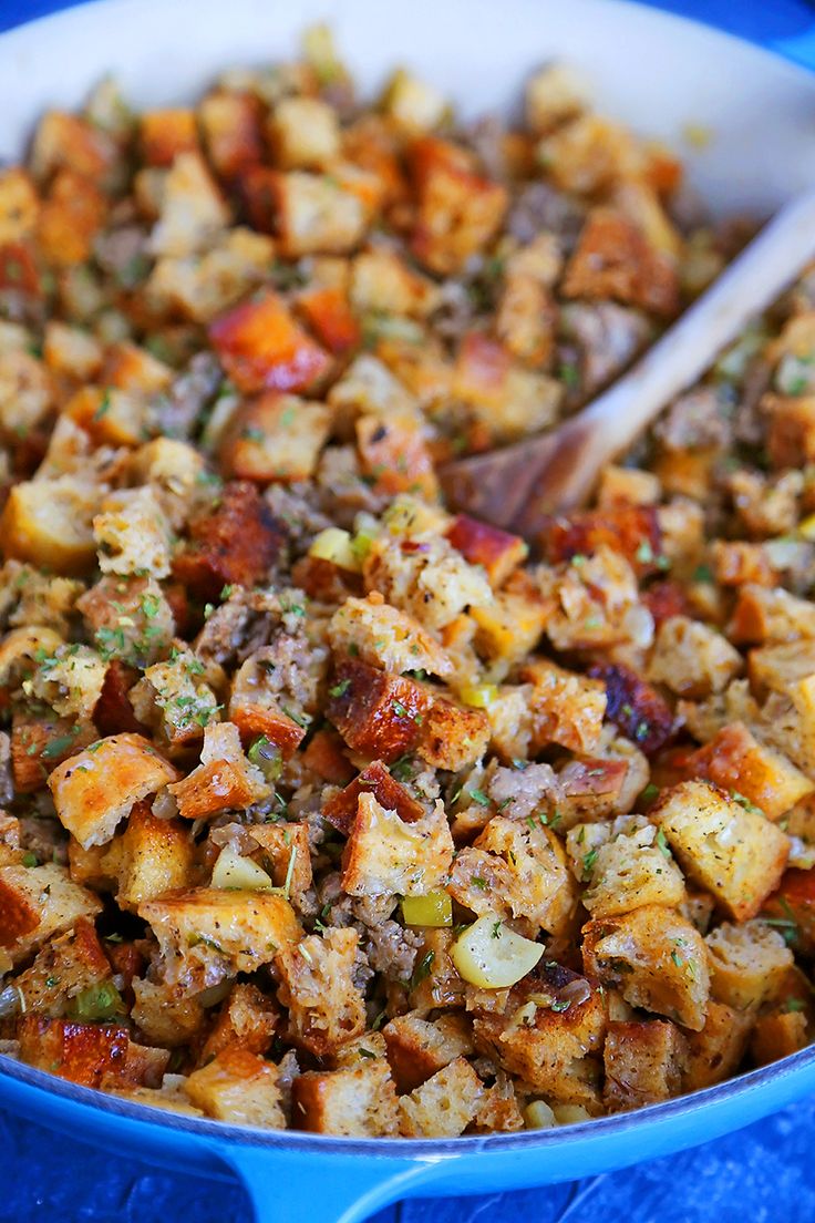 a blue pan filled with stuffing next to a wooden spoon