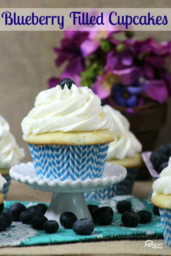 blueberry filled cupcakes with white frosting and blackberries on a cake plate