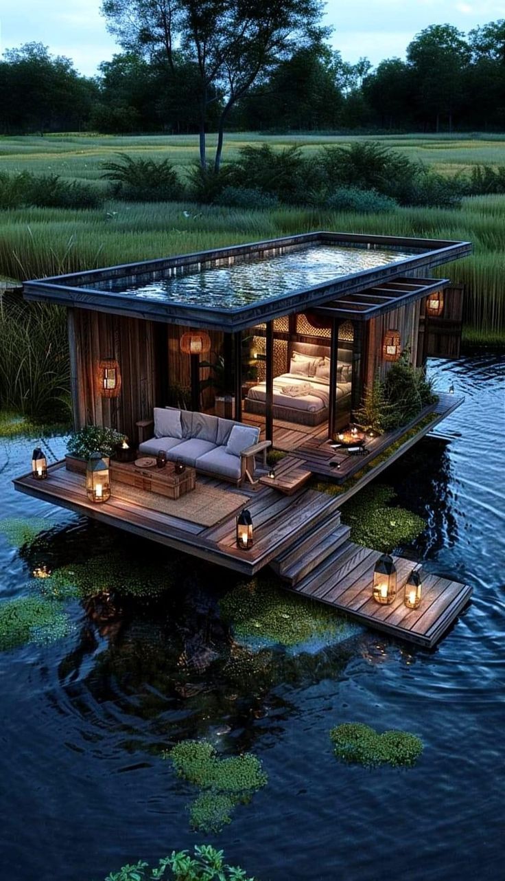 a floating house in the middle of water with candles lit up on it's deck