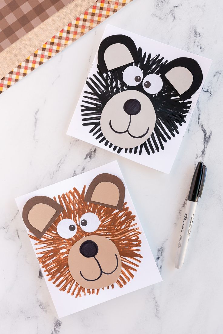 two paper animals on top of a table next to a pen and marker board with the same animal drawn on it