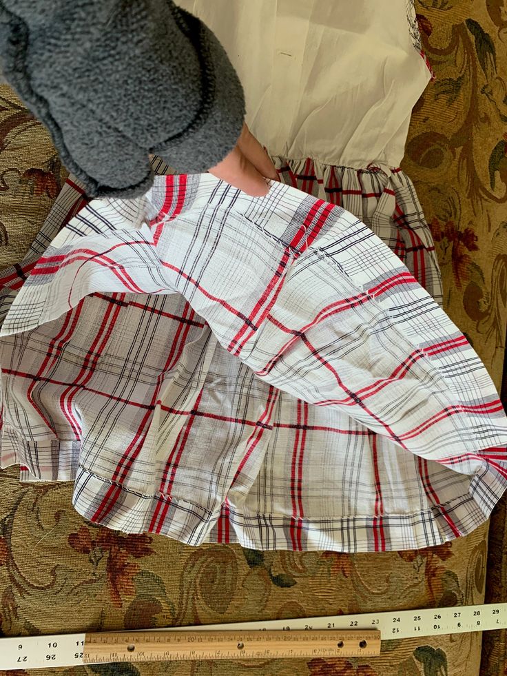 "Vintage cotton dress is made from a white birdseye textured bodice and a red, black, and white gauzy textured skirt gathered into the waist. This same plaid acts as finding along arm holes, neckline and down center front placket, which has 3 decorative black buttons, which look like they may have originally had rhinestones in their centers. It closes with buttons down the center back of bodice- one button is missing. Waistline has a belt carrier on each side. This dress was handmade. Approximat Vintage Cotton Dress, White Plaid Skirt, Textured Skirt, Skirt White, Plaid Skirt, White Sleeveless, Plaid Skirts, Vintage Cotton, Black Button