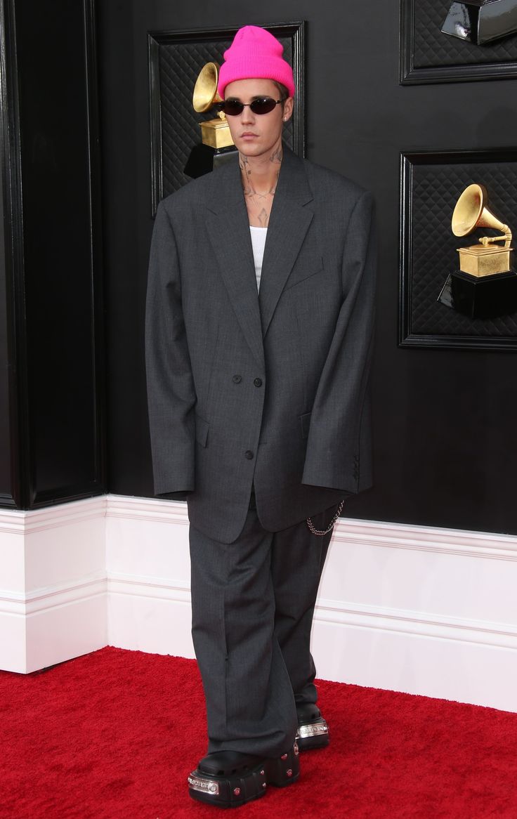 a man in a suit and pink hat on the red carpet