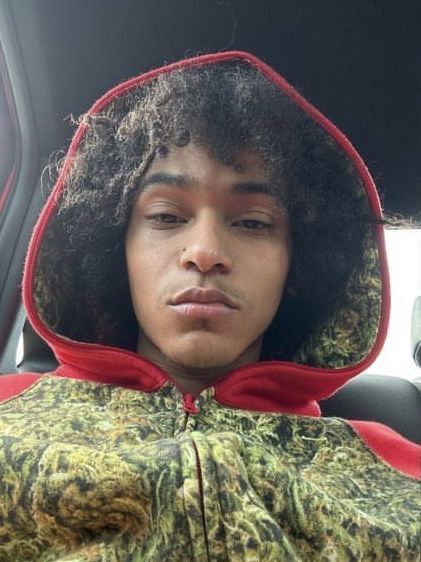 a young man wearing a red hoodie sitting in the back seat of a car