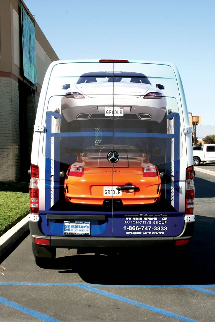 an orange car is in the back of a white van