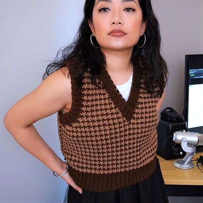 a woman standing in front of a computer desk with her hands on her hips and looking at the camera