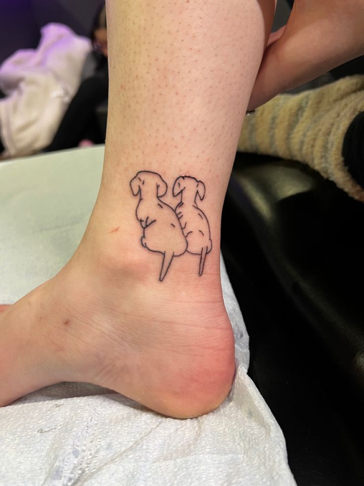 a small tattoo on the ankle of a woman's foot, depicting two sheep