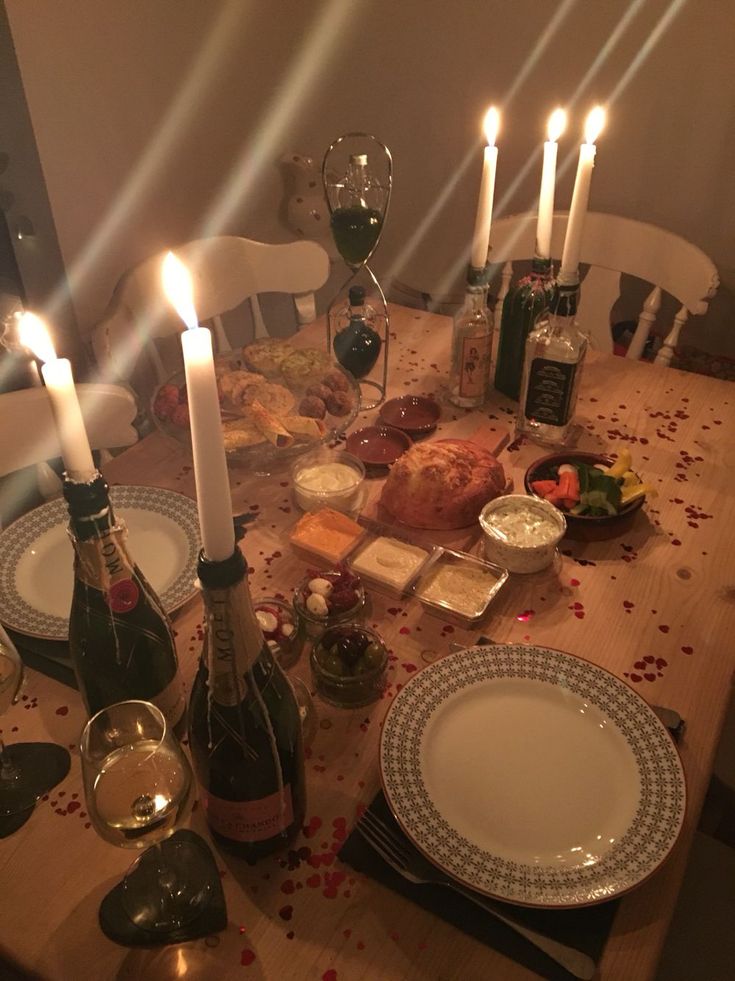 a dinner table is set with wine, food and candles