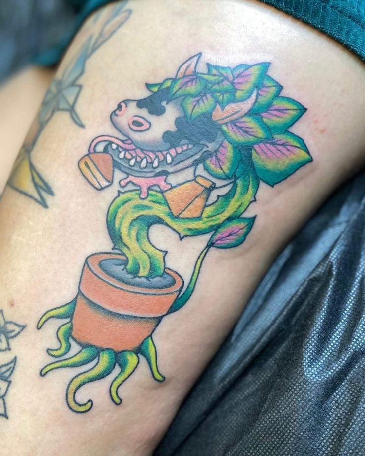 a woman's leg with a tattoo on it that has an image of a dog holding a potted plant