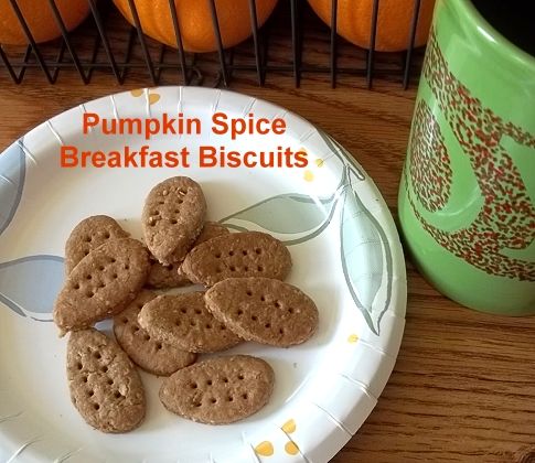 pumpkin spice breakfast biscuits on a paper plate next to a green mug and oranges