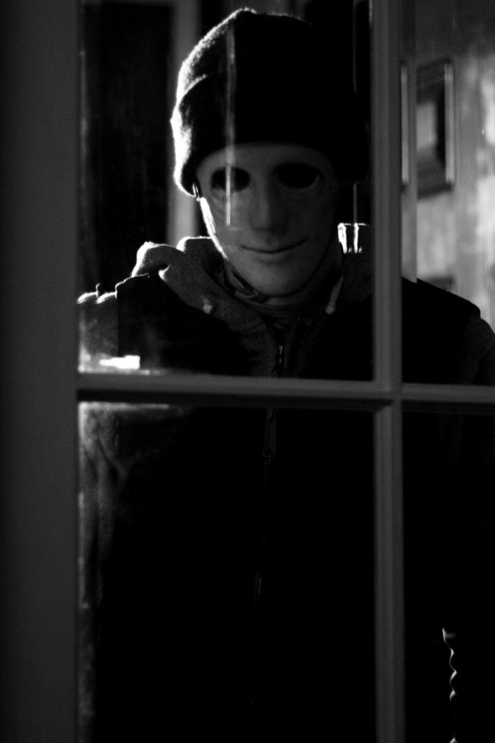 a person wearing a mask looking through a window