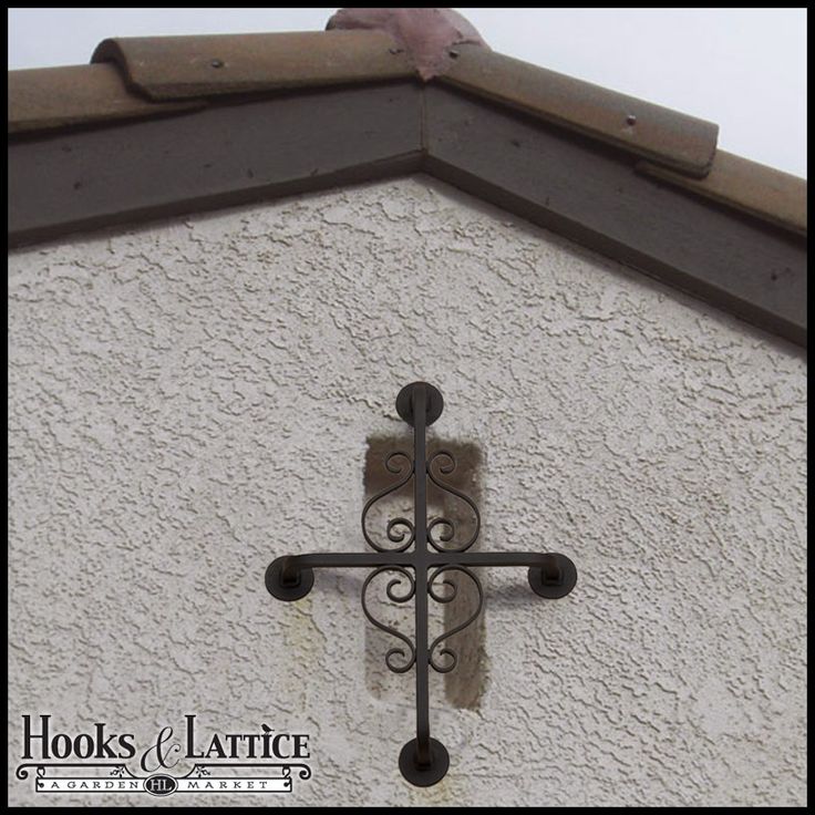 a cross on the side of a building with a bird perched on it's roof