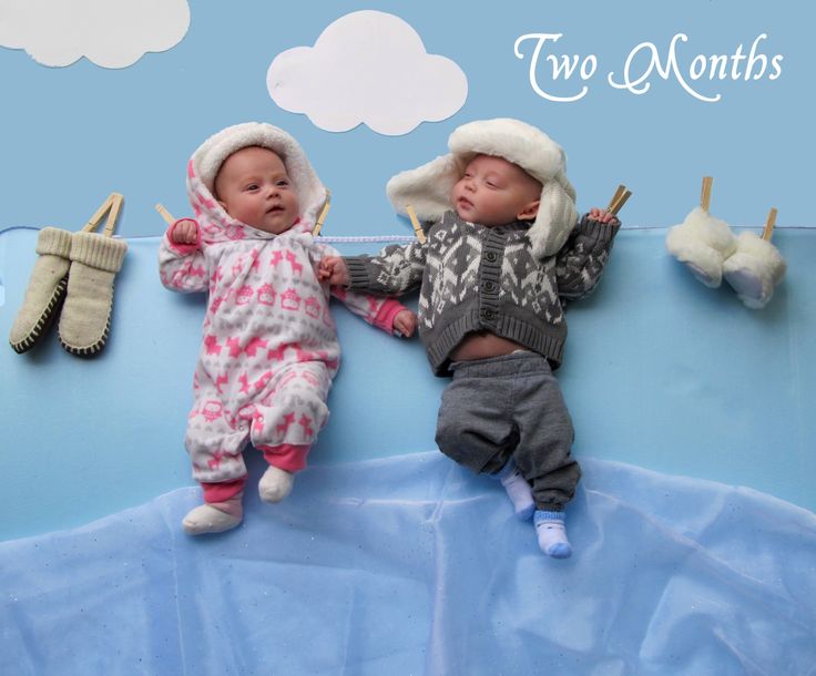 two babies laying next to each other on top of a blue surface with clothes hanging from clothes pins