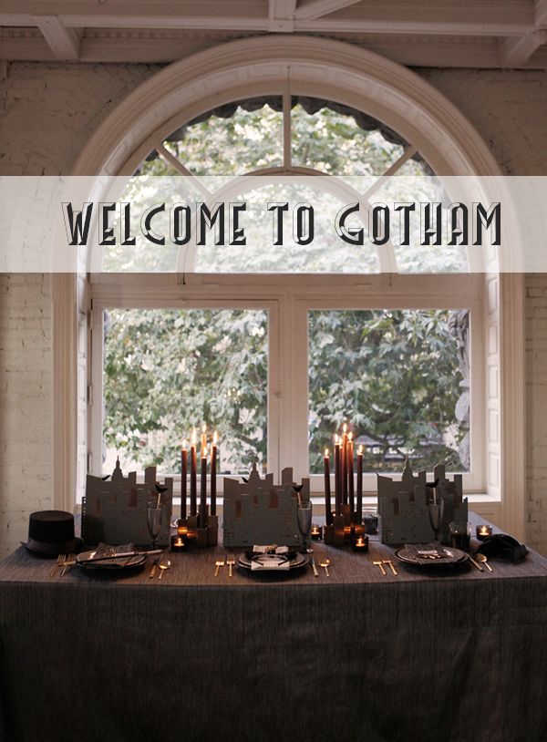 a table with candles and place settings in front of a window that says welcome to gotham