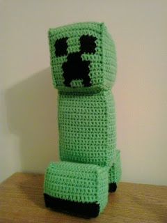 a crocheted green object sitting on top of a wooden table