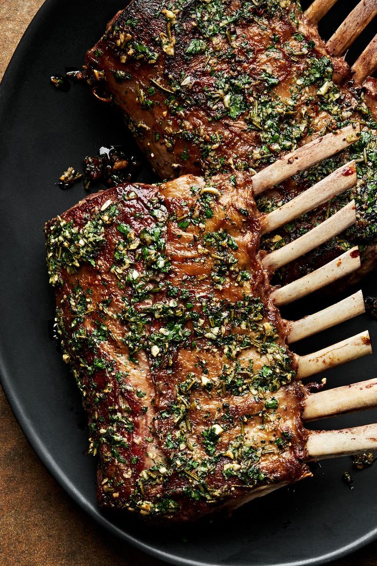 two pieces of meat on a black plate with parsley sprinkled on top