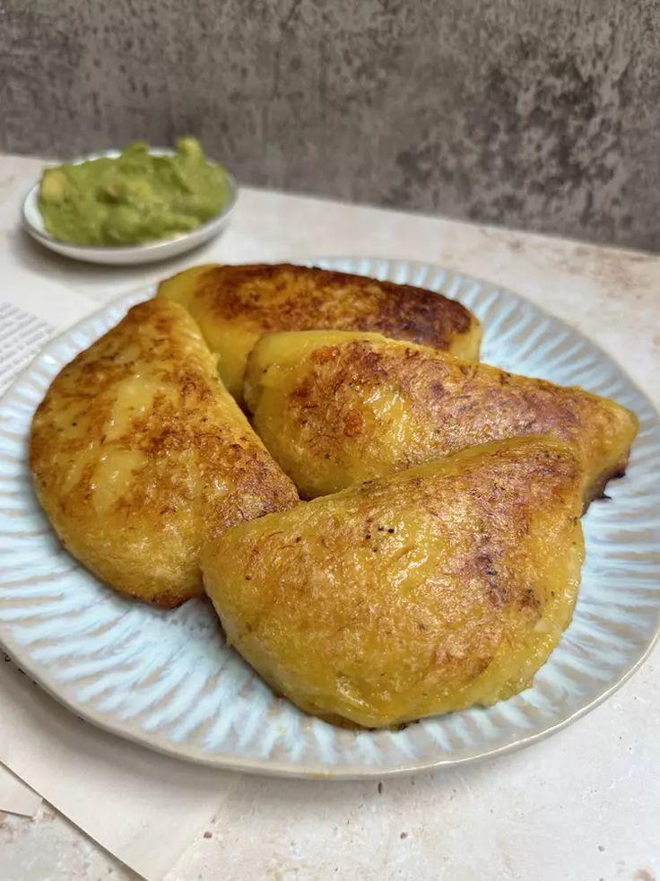 some food is sitting on a plate with guacamole in the bowl next to it