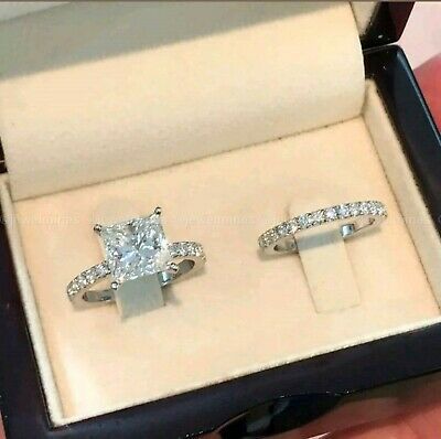 an open box with two rings in it and the ring has a princess cut diamond