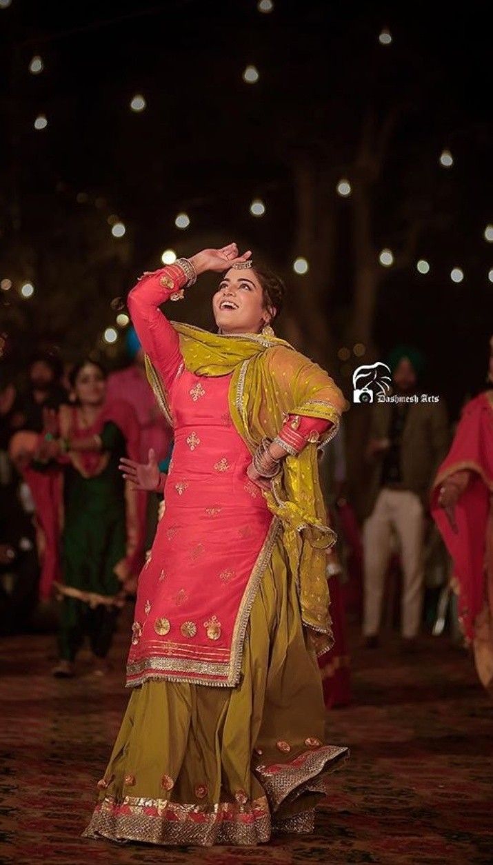 a woman in a red and yellow outfit dancing on the dancefloor at night