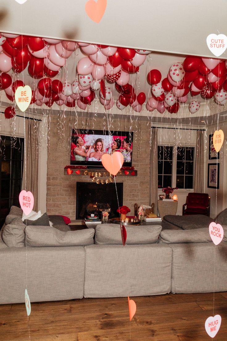 a living room filled with furniture and lots of balloons hanging from the ceiling next to a fire place