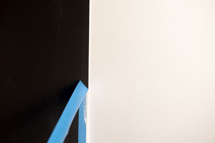 the corner of a wall is painted white and has blue tape on it with a black background