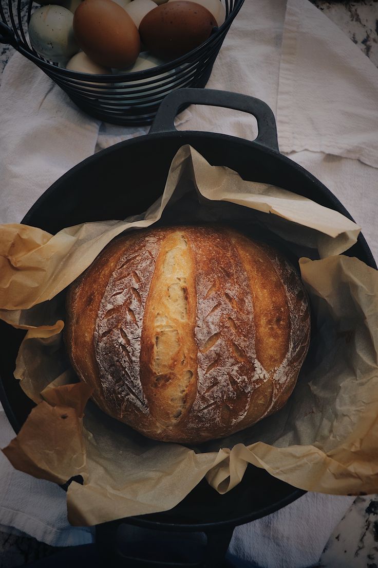 a loaf of bread sitting in a pan on top of a table next to eggs