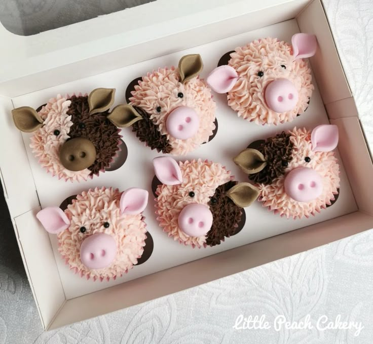 cupcakes decorated with pink frosting and brown sheep's heads in a box