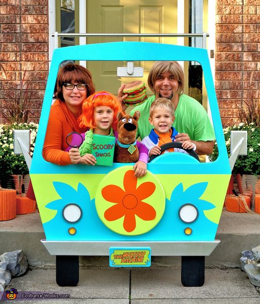 three adults and two children posing in the back of a bus with flowers on it