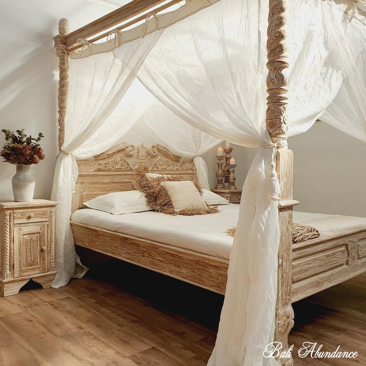 a bed with white drapes and pillows on it