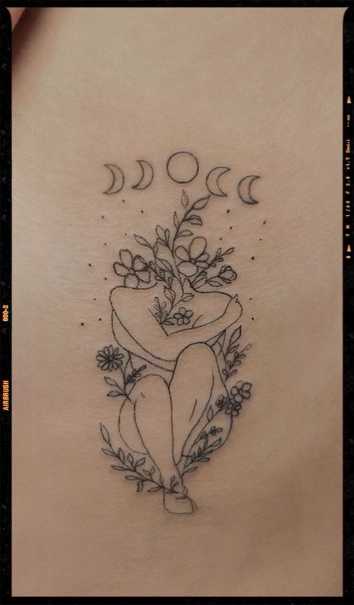 the back of a woman's stomach with flowers and moon tattoos on her ribs