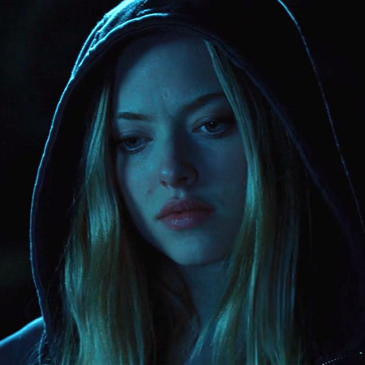 a woman with long blonde hair wearing a black hoodie and looking at the camera