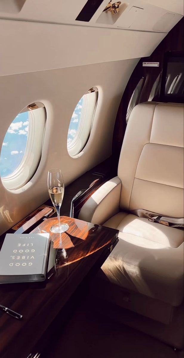 the interior of an airplane with two wine glasses and a book sitting on a table