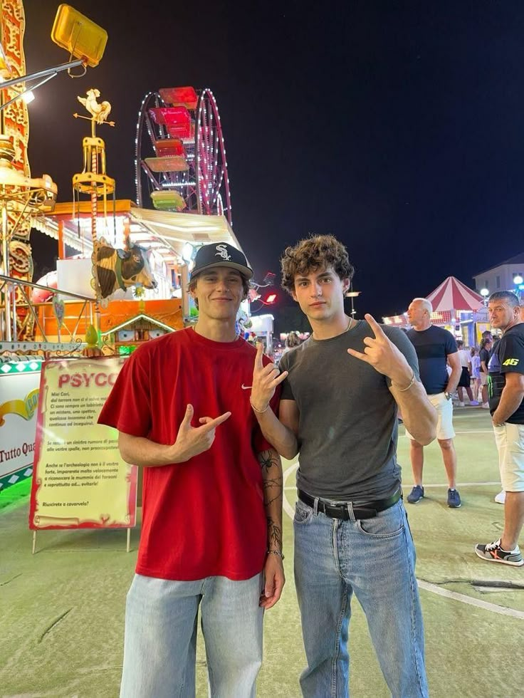 two young men standing next to each other at an amusement park