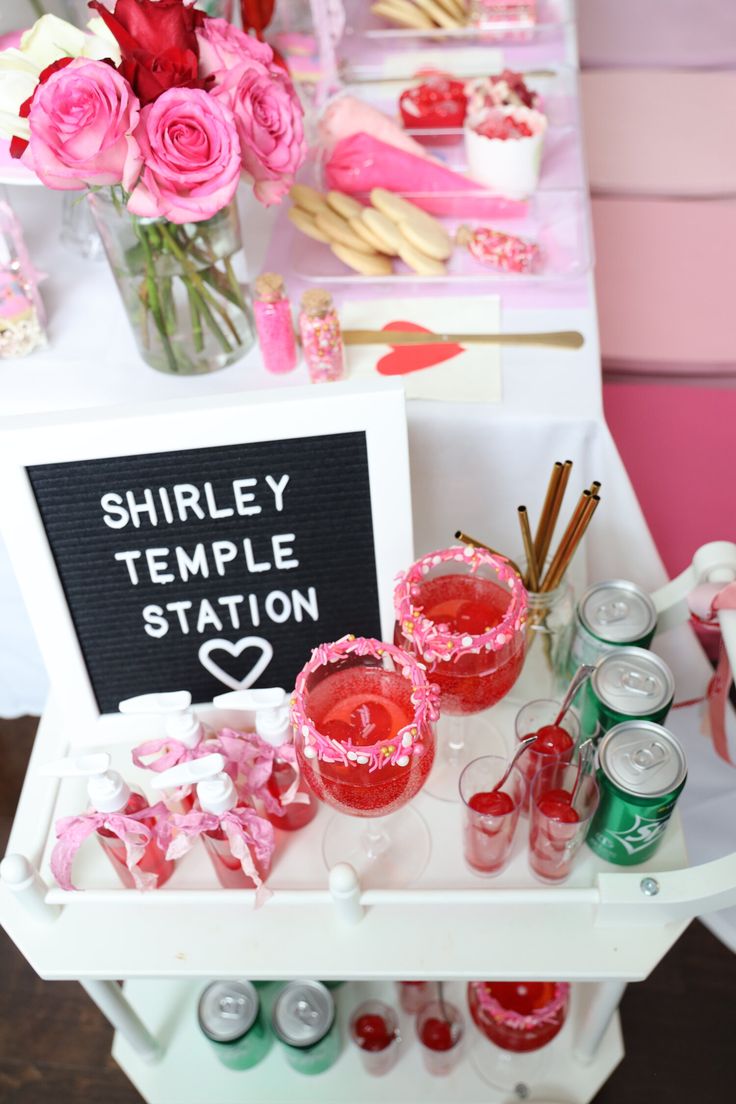 there is a table with pink and red items on it, including candles, tea cups, and candy