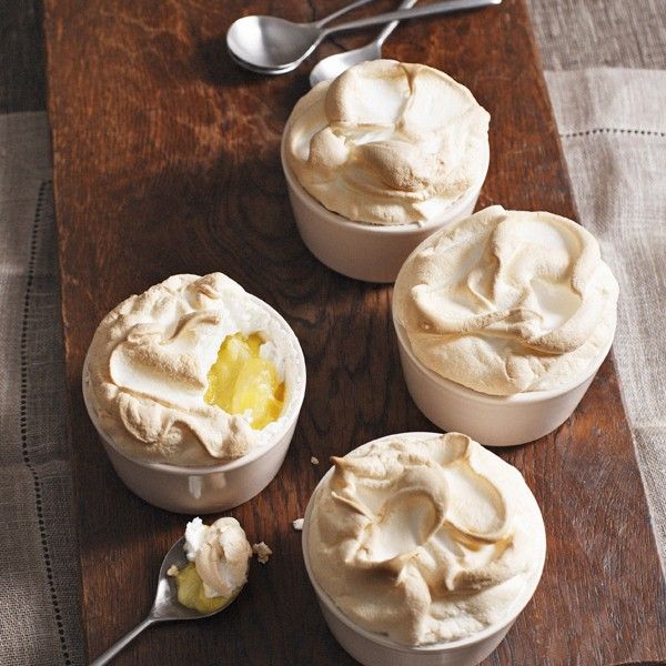 four desserts are sitting on a table with spoons