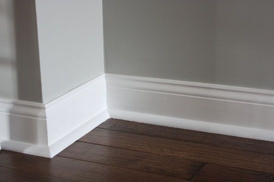 the corner of an empty room with wood flooring and white trim on the walls