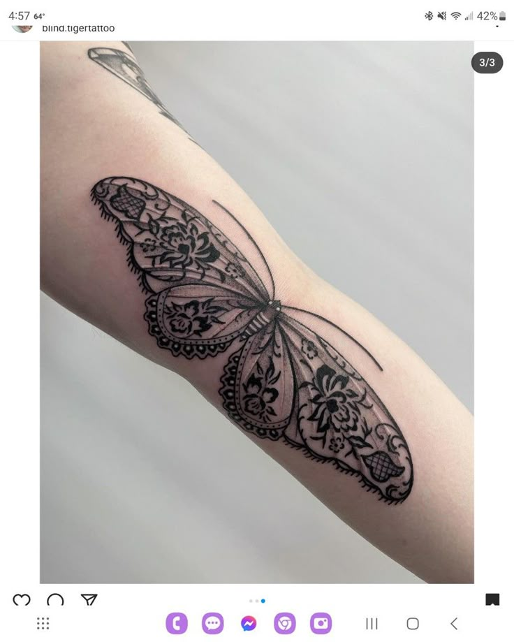 a black and white butterfly tattoo on the left arm, with lacework details around it