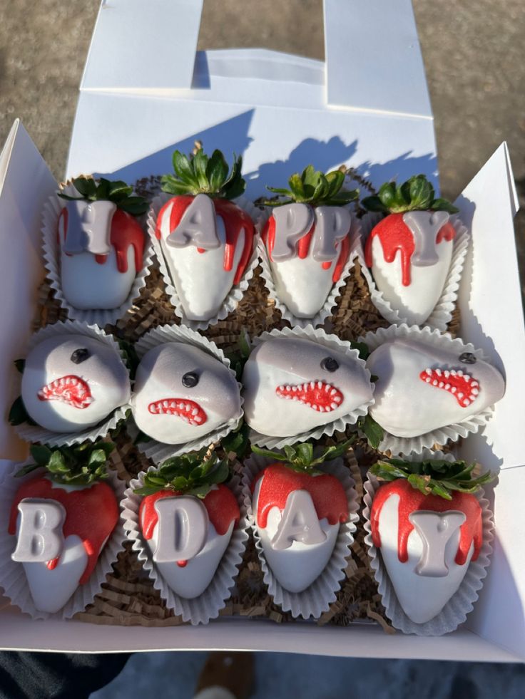 a box filled with chocolate covered strawberries in the shape of shark heads and teeth