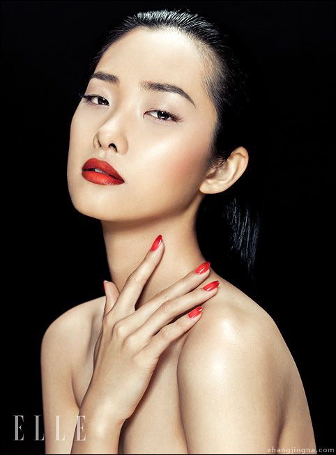 a woman with red nail polish on her chest and hand over her shoulder, posing for the camera