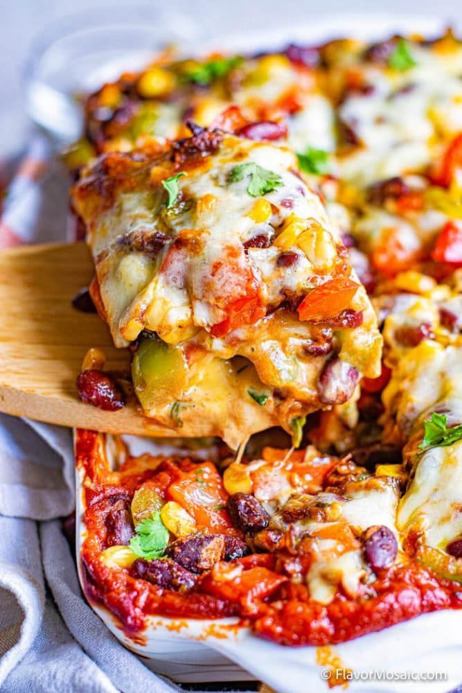 a white plate topped with lasagna casserole covered in cheese and vegetables