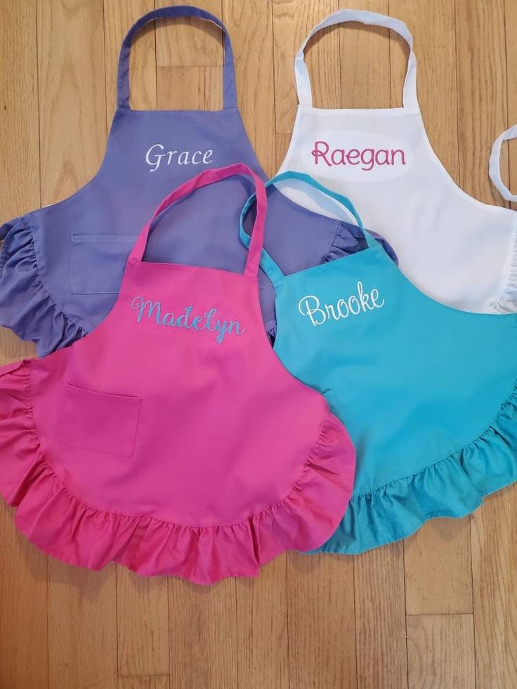 three children's aprons with personalized names on them