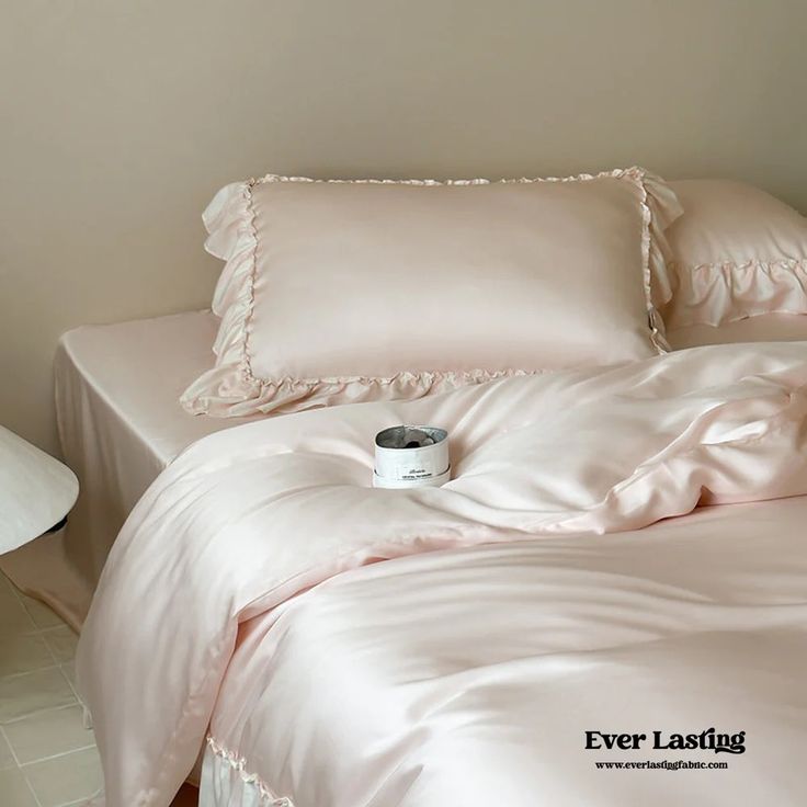 a pink comforter with ruffled edges and a cup of coffee on the bed