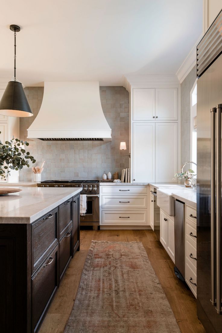 a kitchen with an area rug in front of the stove and refrigerator, along with two pendant lights