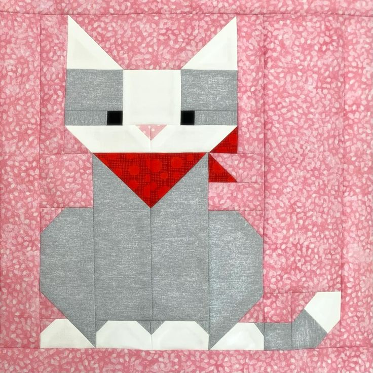 a gray and white cat sitting on top of a pink quilted wall hanger