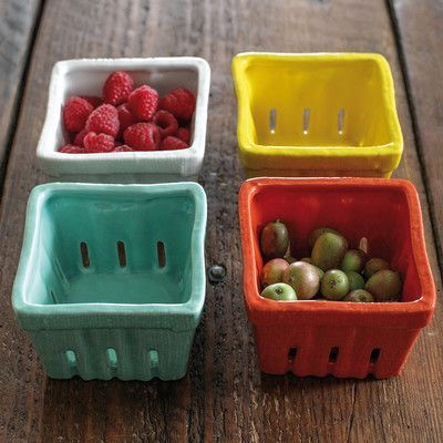 four plastic containers with raspberries and grapes in them on a wooden table top