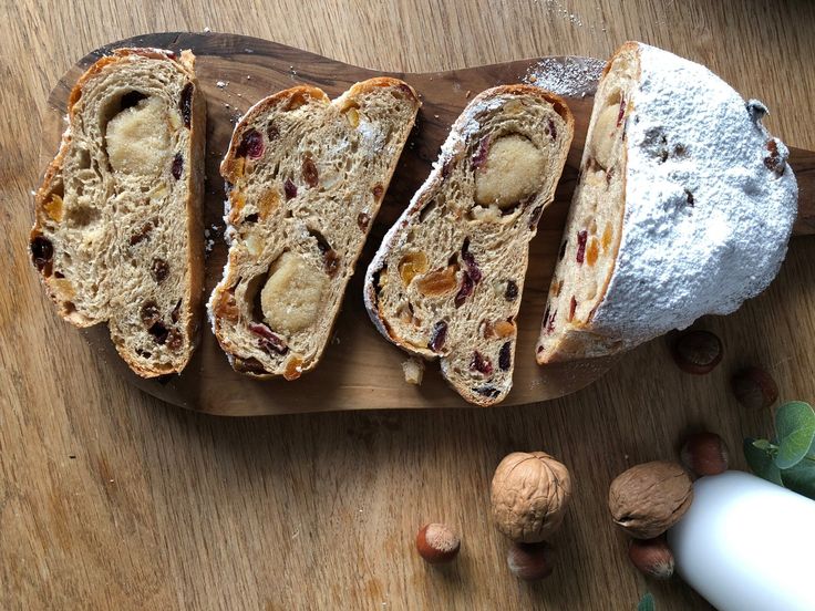 several pieces of bread sitting on top of a wooden cutting board next to nuts and other food